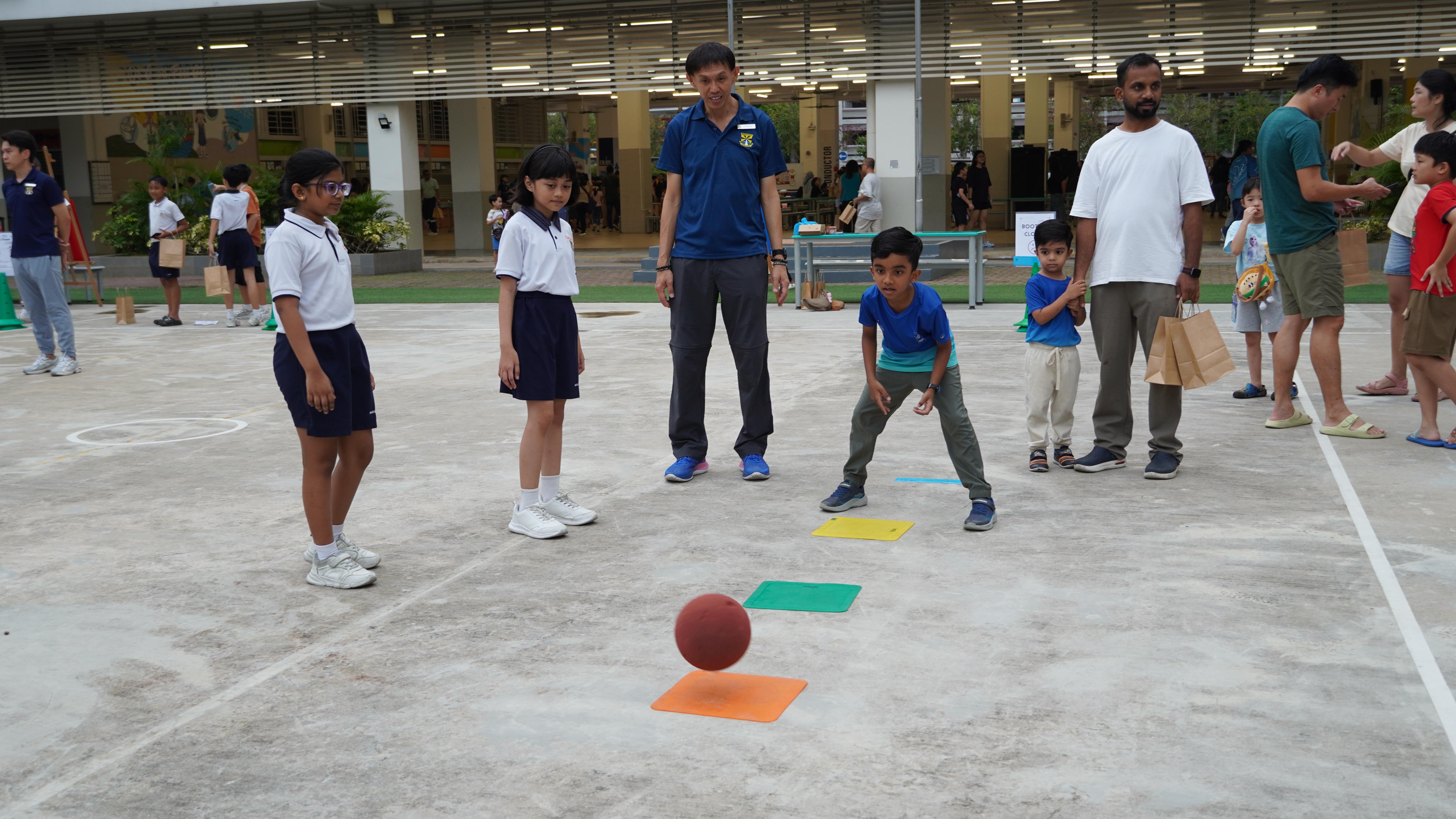 Eyes on the prize! With everyone watching closely, our student put his aim and control to the test as he sends the ball towards the colourful targets.